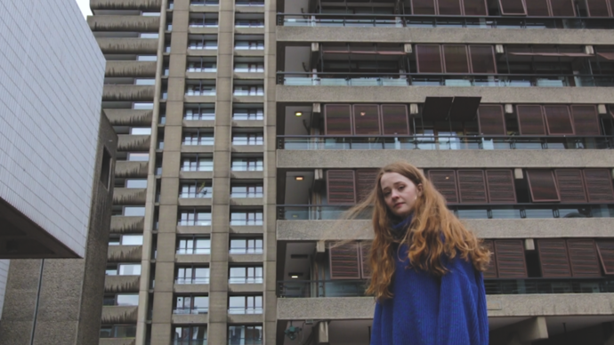 photo of young poet laurie ogden standing in front of barbican towers